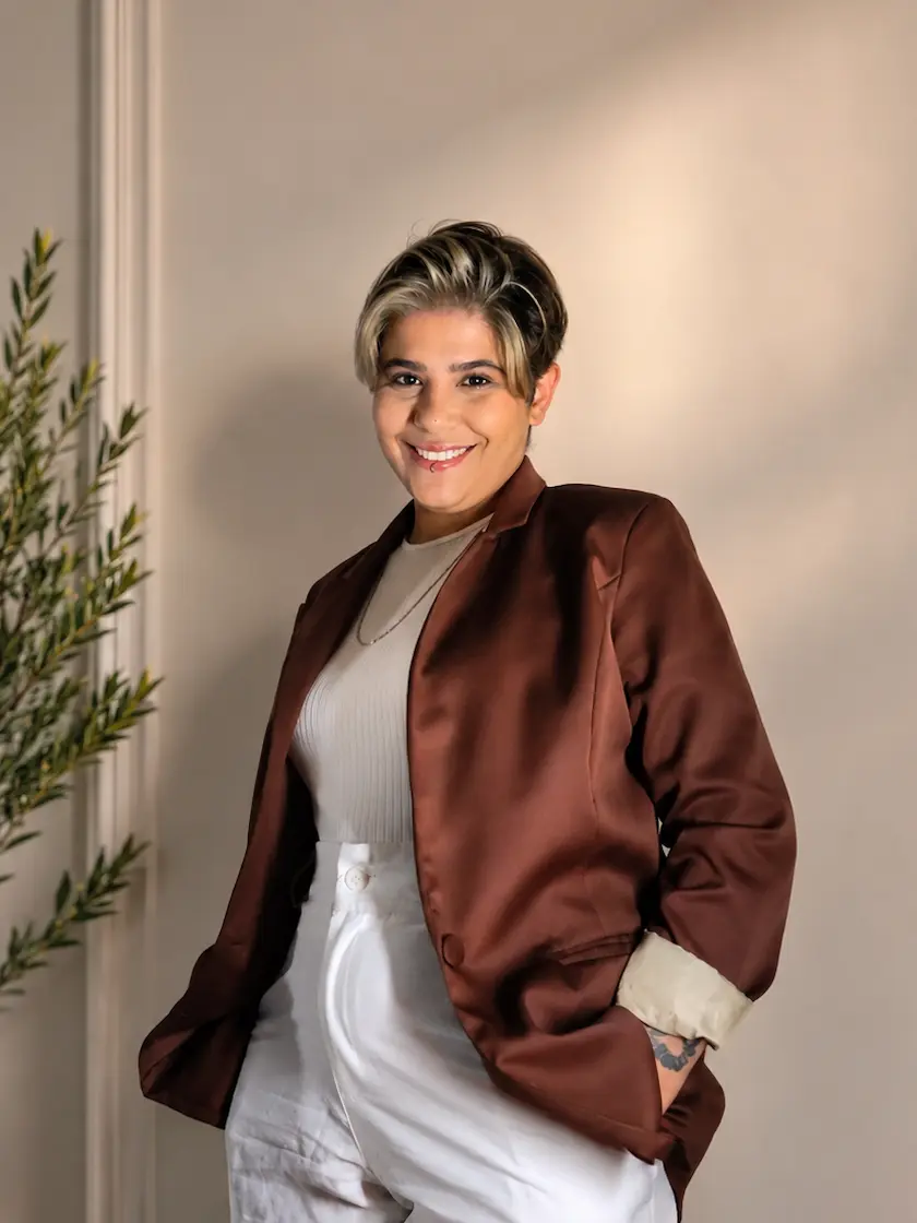 Carol, corretora parceira Cury, sorrindo com os braços cruzados